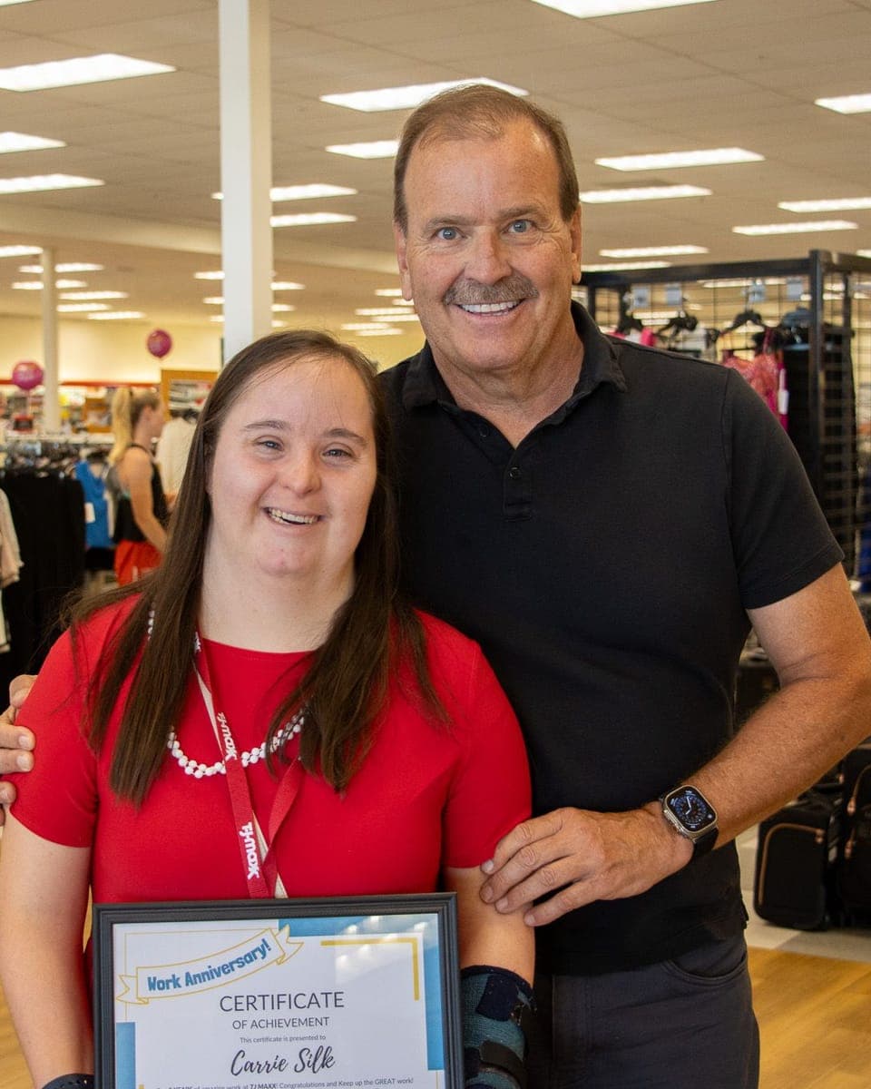 A woman and man smiling in TJMaxx, celebrating the woman who has worked there for 3 years